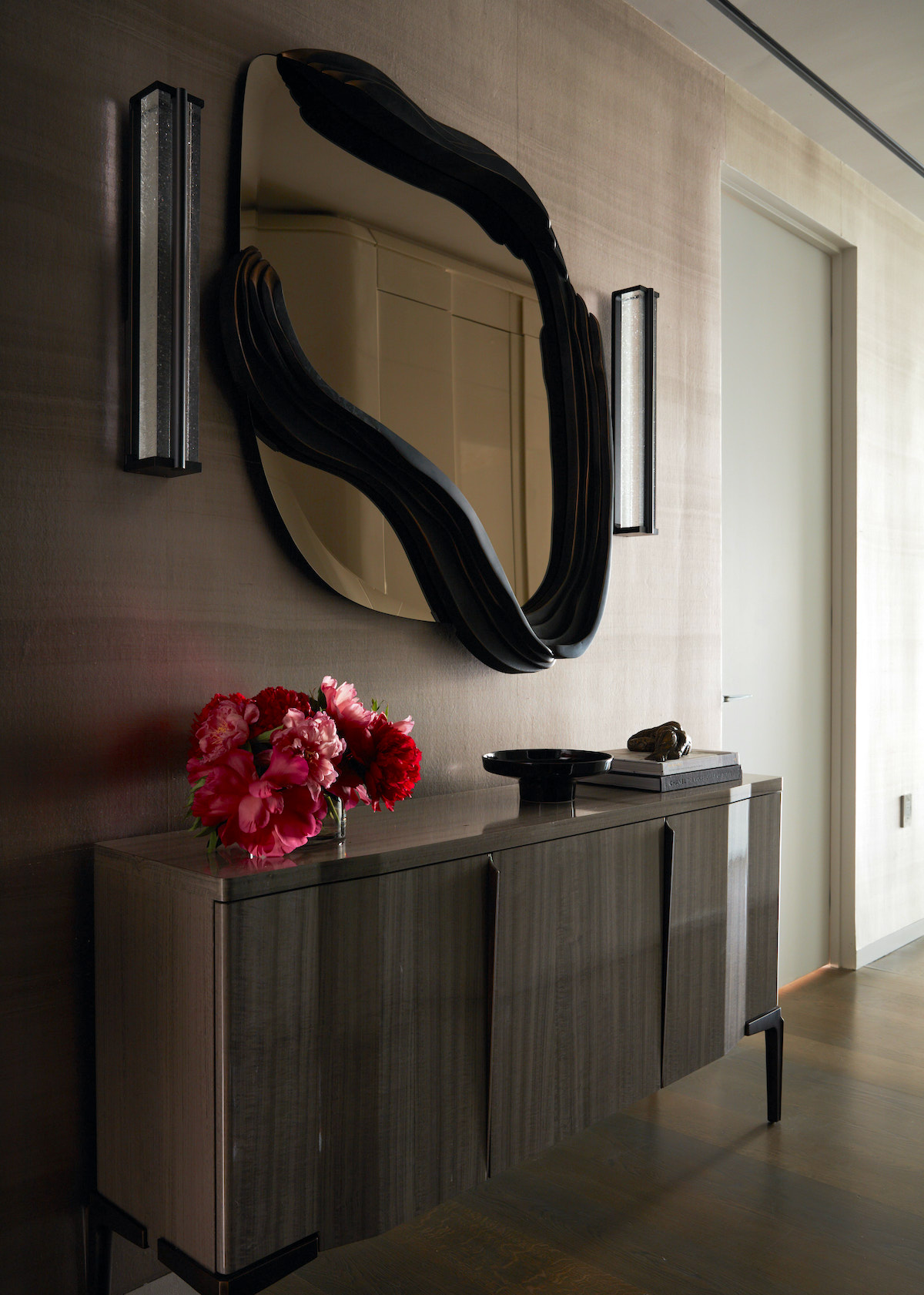 Contemporary styled mirror over a contemporary cabinet.