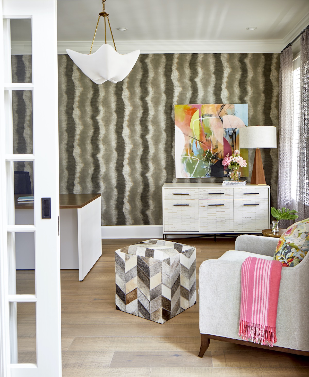 Neutral furniture complements a room with striped wallpaper.