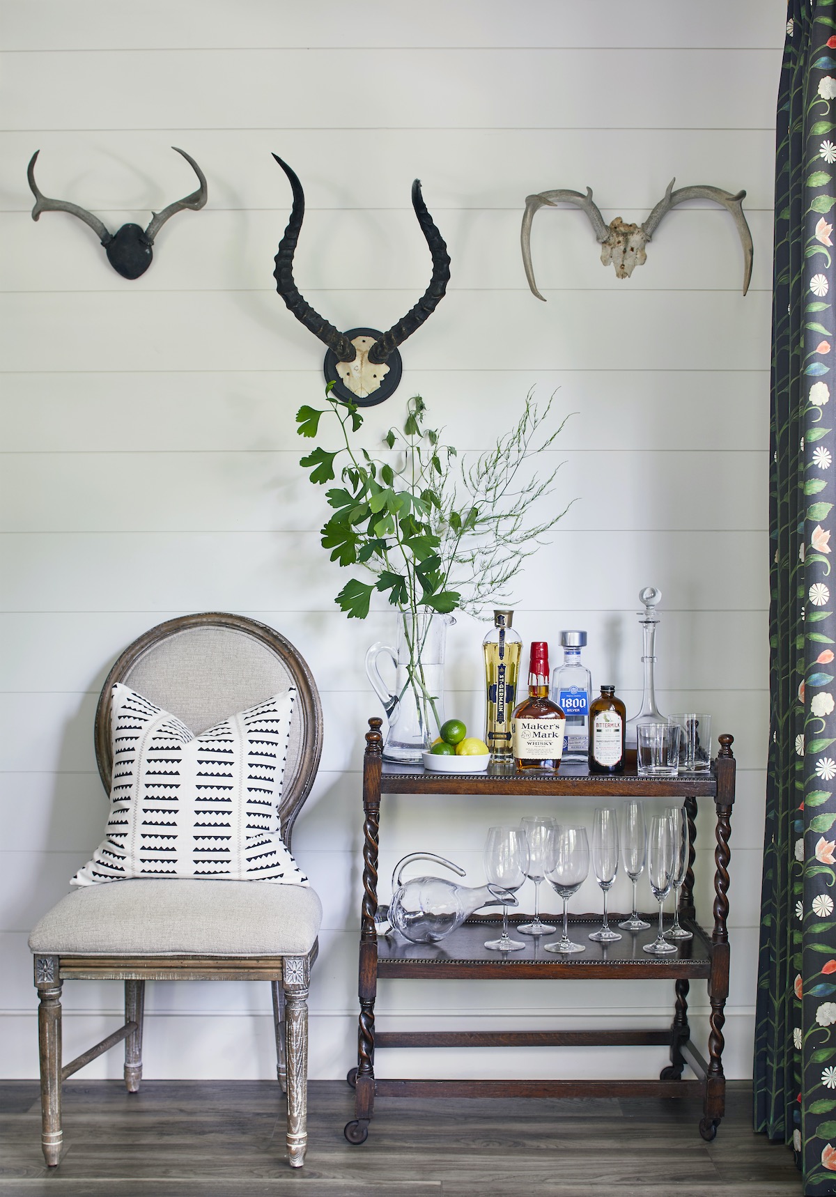 A set of three antlers hang above a chair and wet bar.