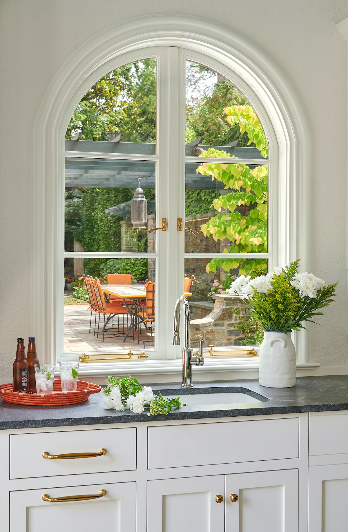 An arched window over the sink opens to pass food and drinks to the pergola dining area beyond.