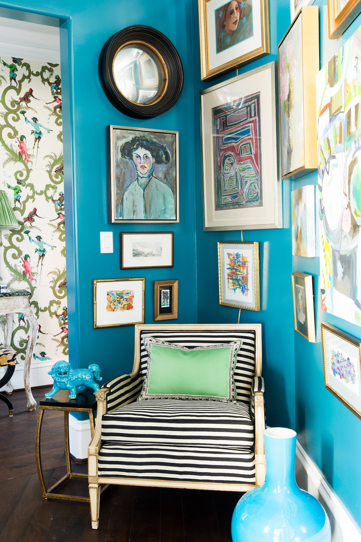 Teal painted room with a striped chair and gallery wall.